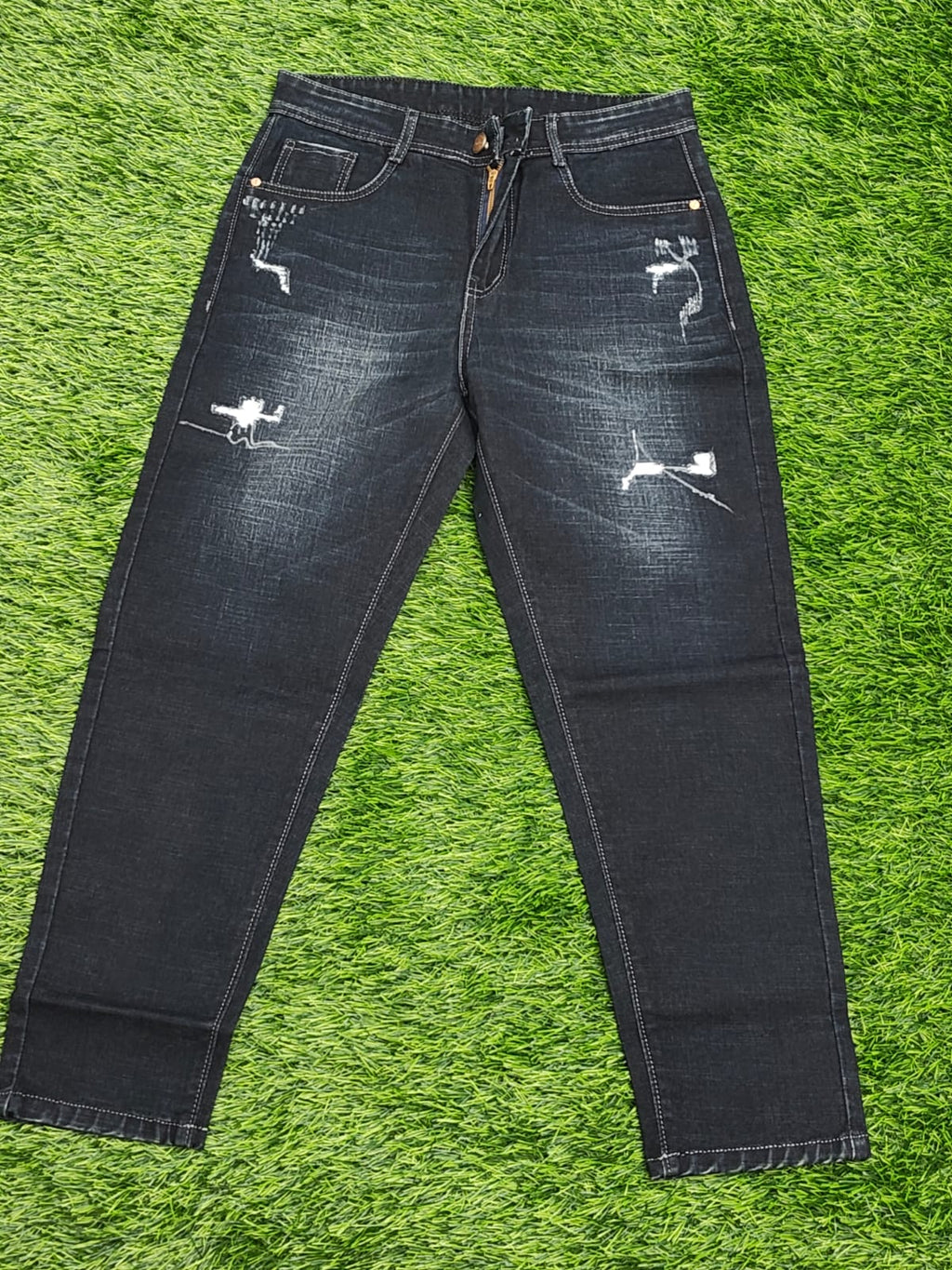 Distressed black jeans on a green grass background