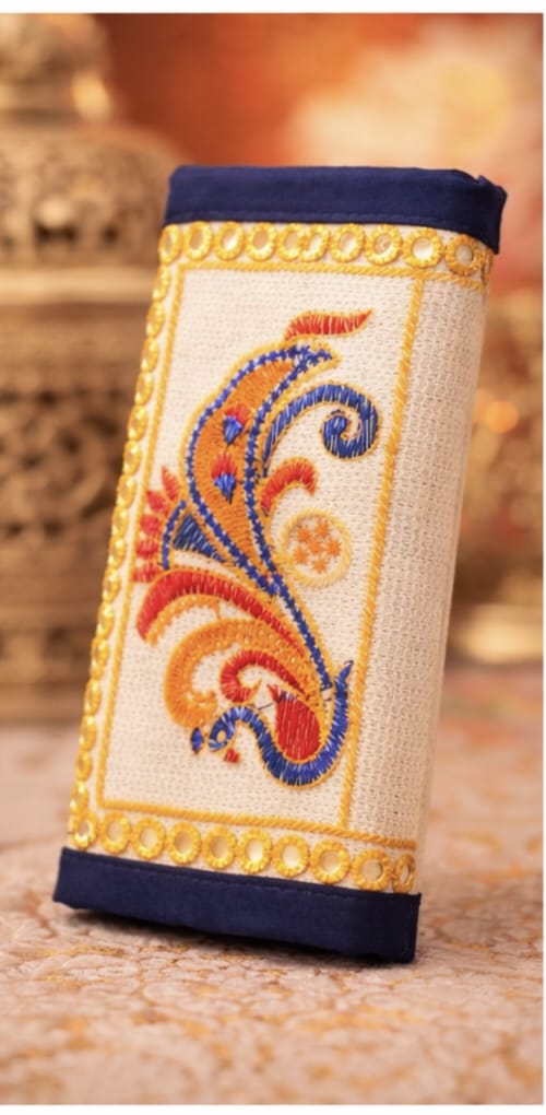Decorative pouch with embroidered design on a wooden surface